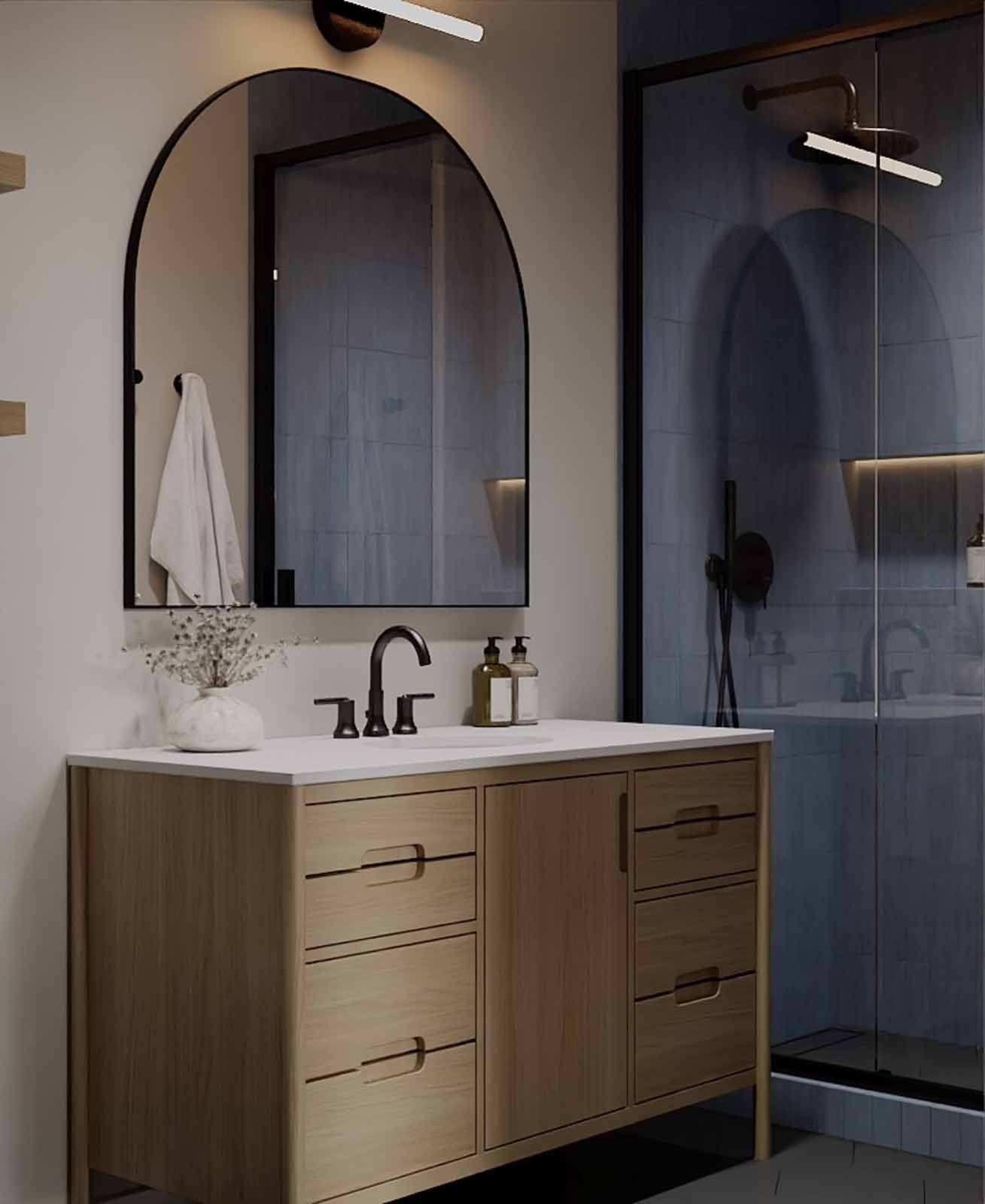 Transitional bathroom with oak vanity, arched mirror, and blue-grey tile shower