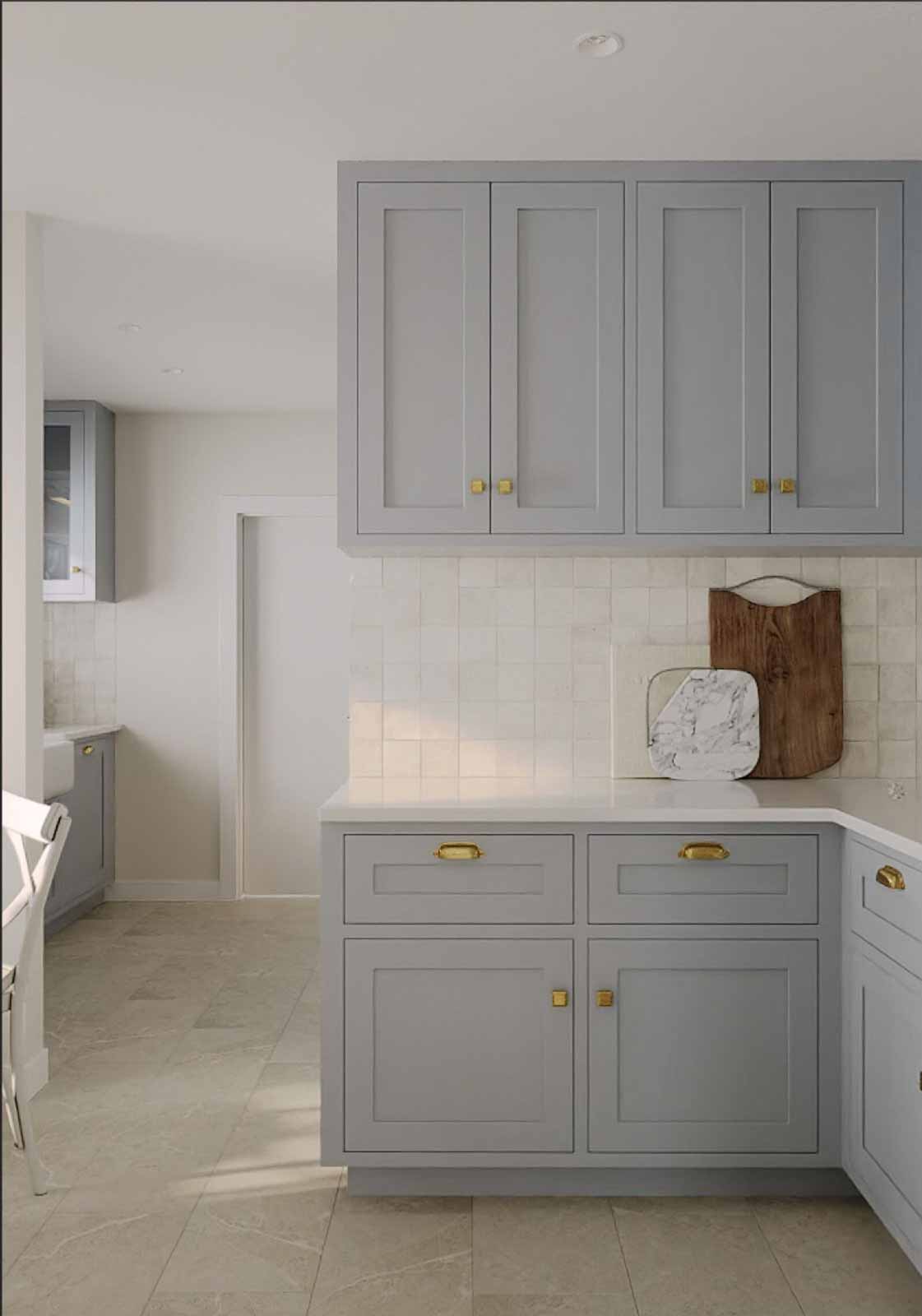 French country kitchen with dove gray shaker cabinets, zellige tile backsplash, and brass hardware
