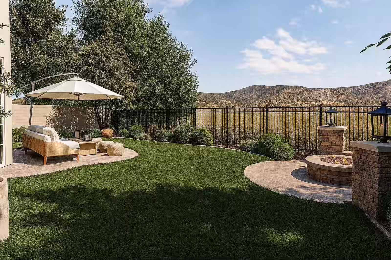 Backyard lounge area with wicker daybed, umbrella, stone fire pit, and mountain views
