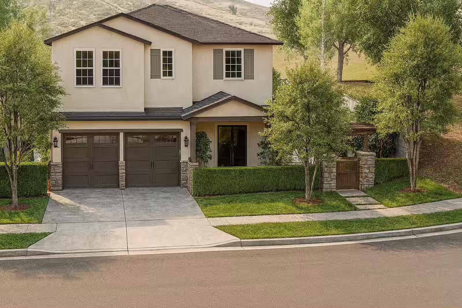 Aerial view of Mediterranean home with manicured hedges, double garage, and stone entry