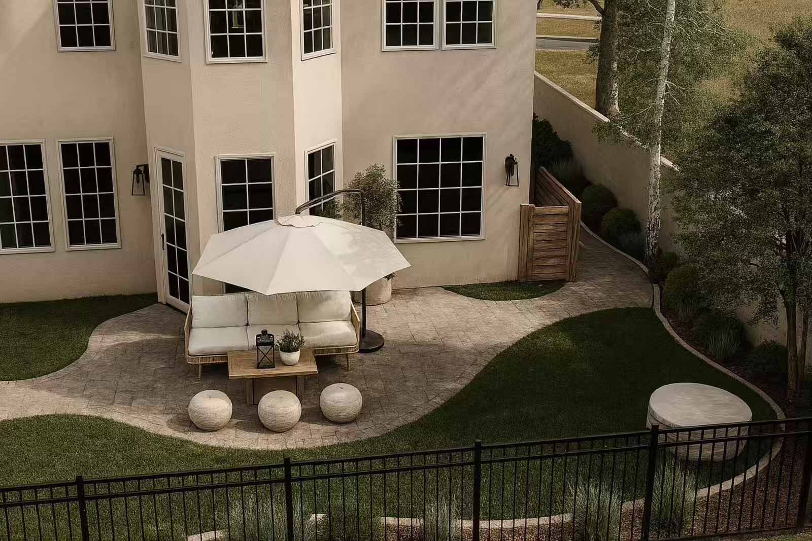 Aerial backyard view with organic paver patio, lounge furniture, and curved lawn design