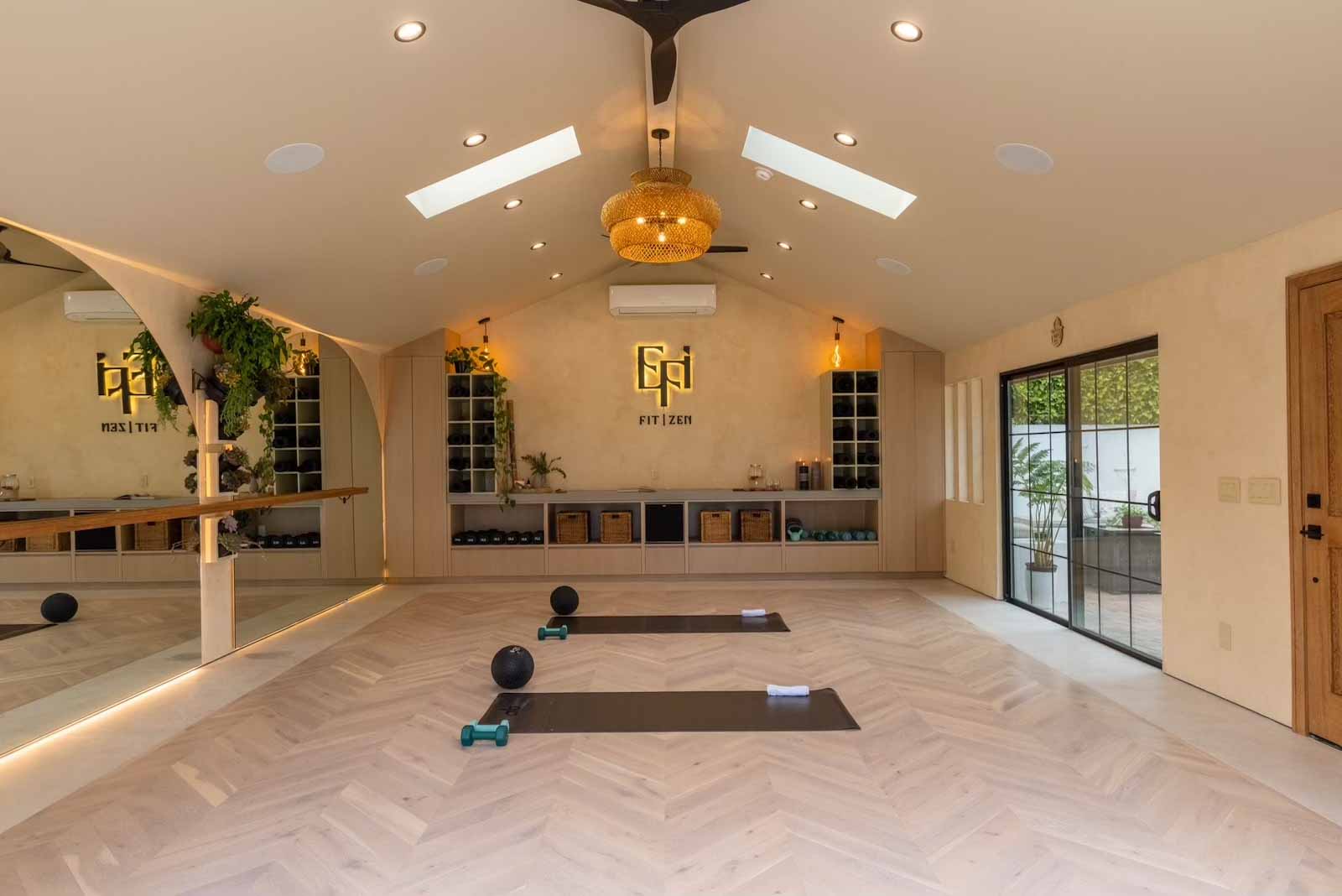 Yoga space with black ceiling fans, rattan chandelier, and skylights