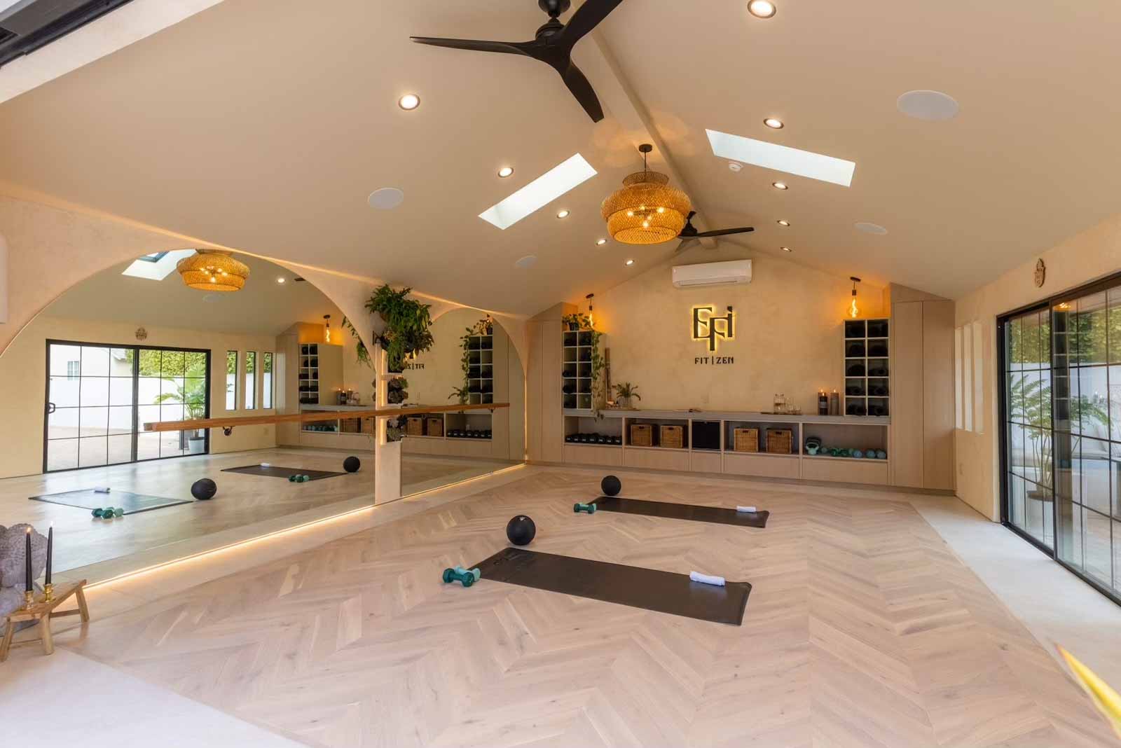 Wide angle of yoga studio showing arched mirrors, storage, and natural light