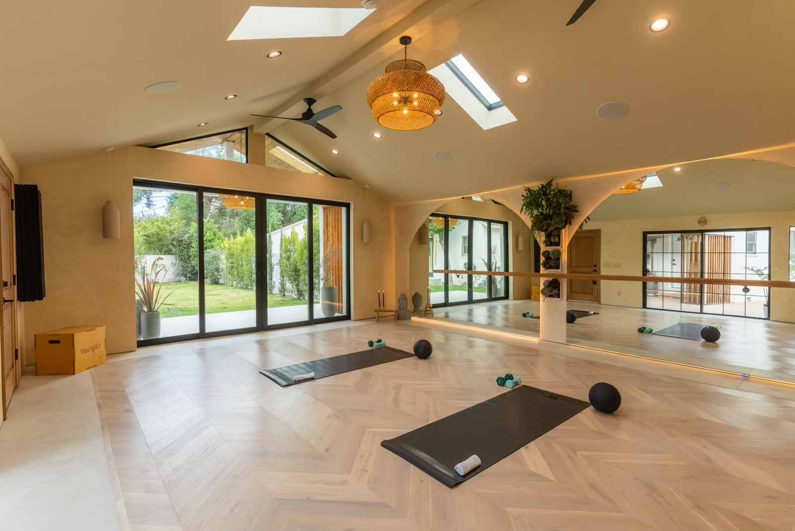 Large yoga studio with multiple windows, skylights, and herringbone floors