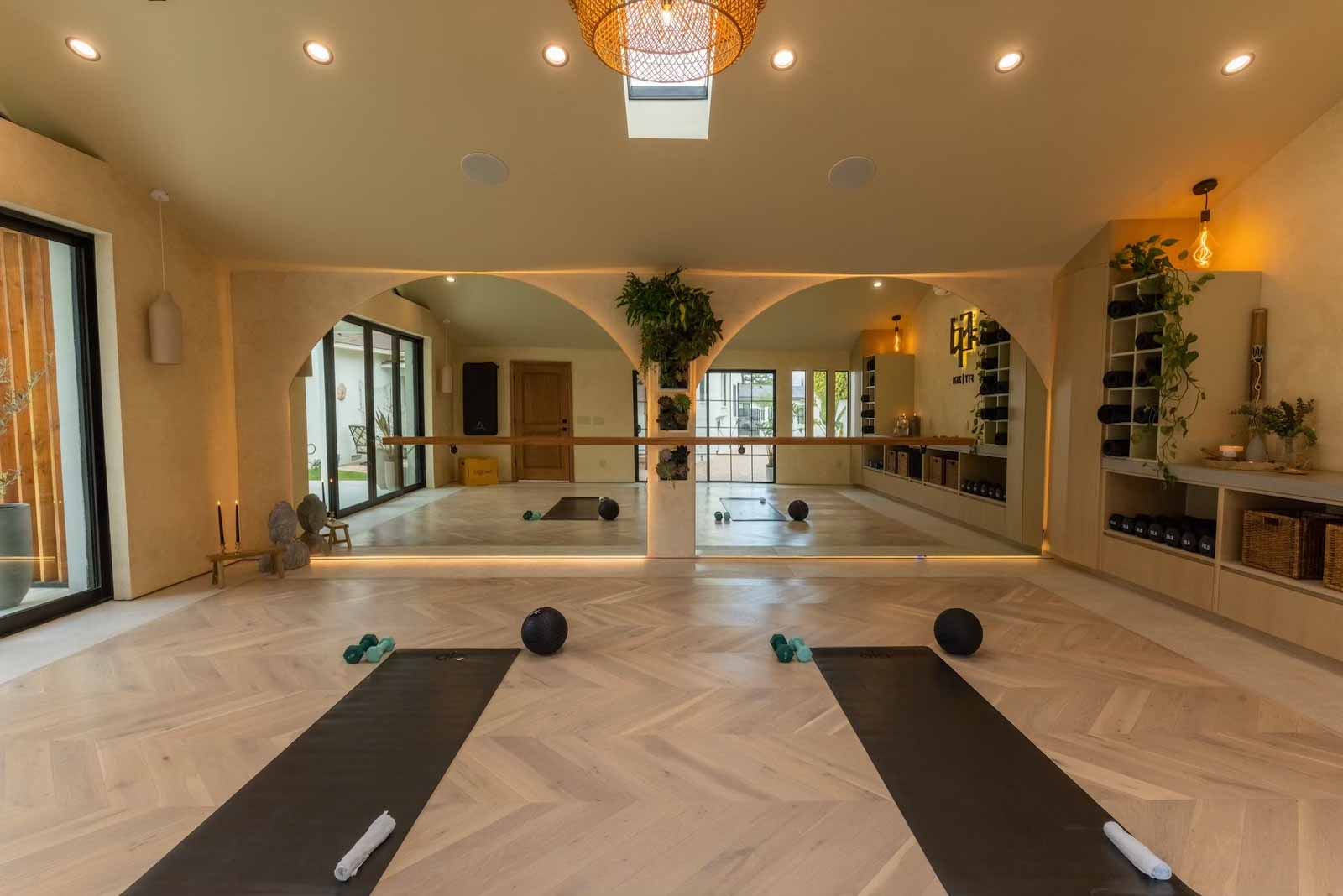 Yoga studio showing arched mirrors, storage wall, and workout equipment