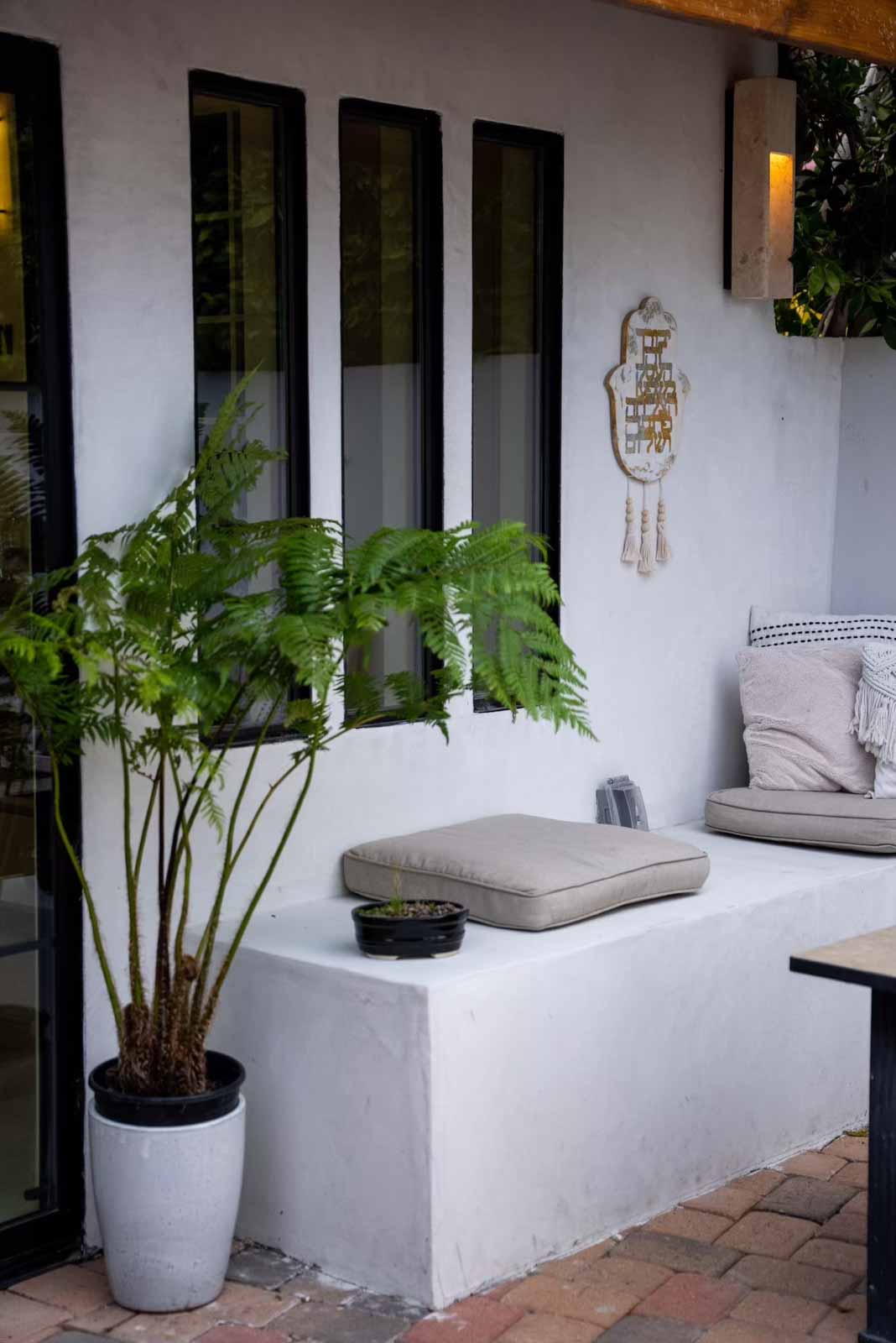 Built-in outdoor bench with fern planter and hamsa wall art