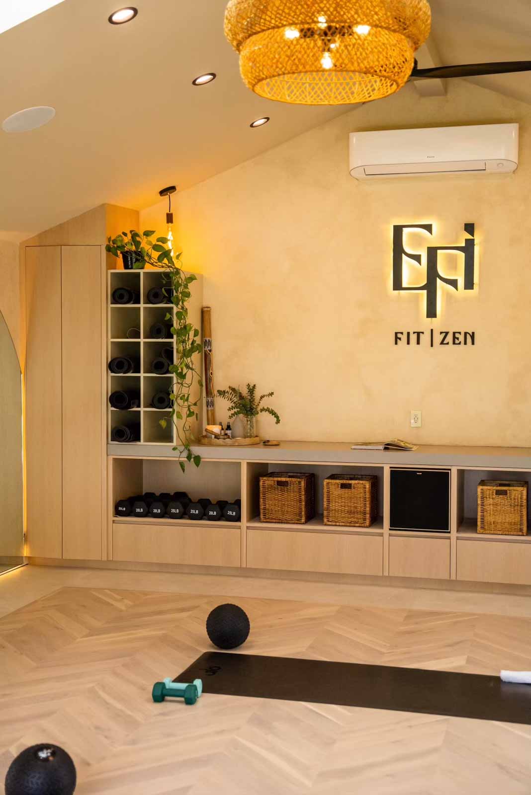 Custom storage with yoga mats, dumbbells, baskets, and FIT ZEN branding