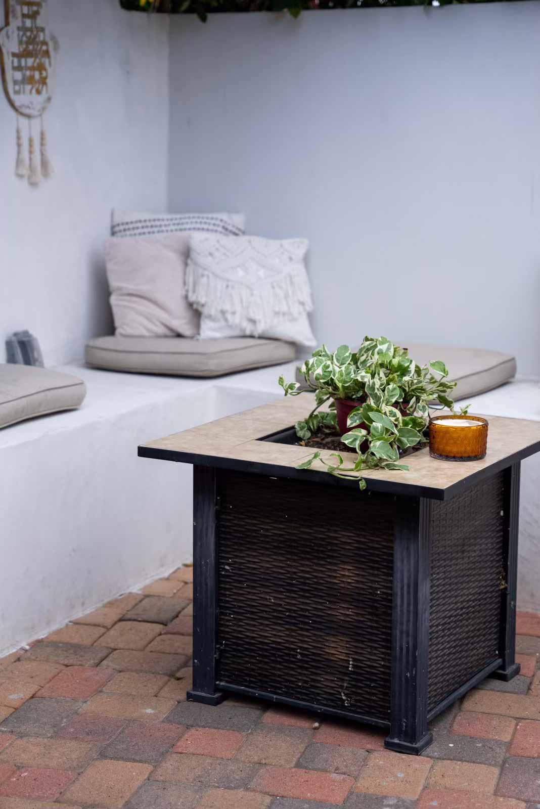 Outdoor seating nook with cushions, throw pillows, and fire pit table