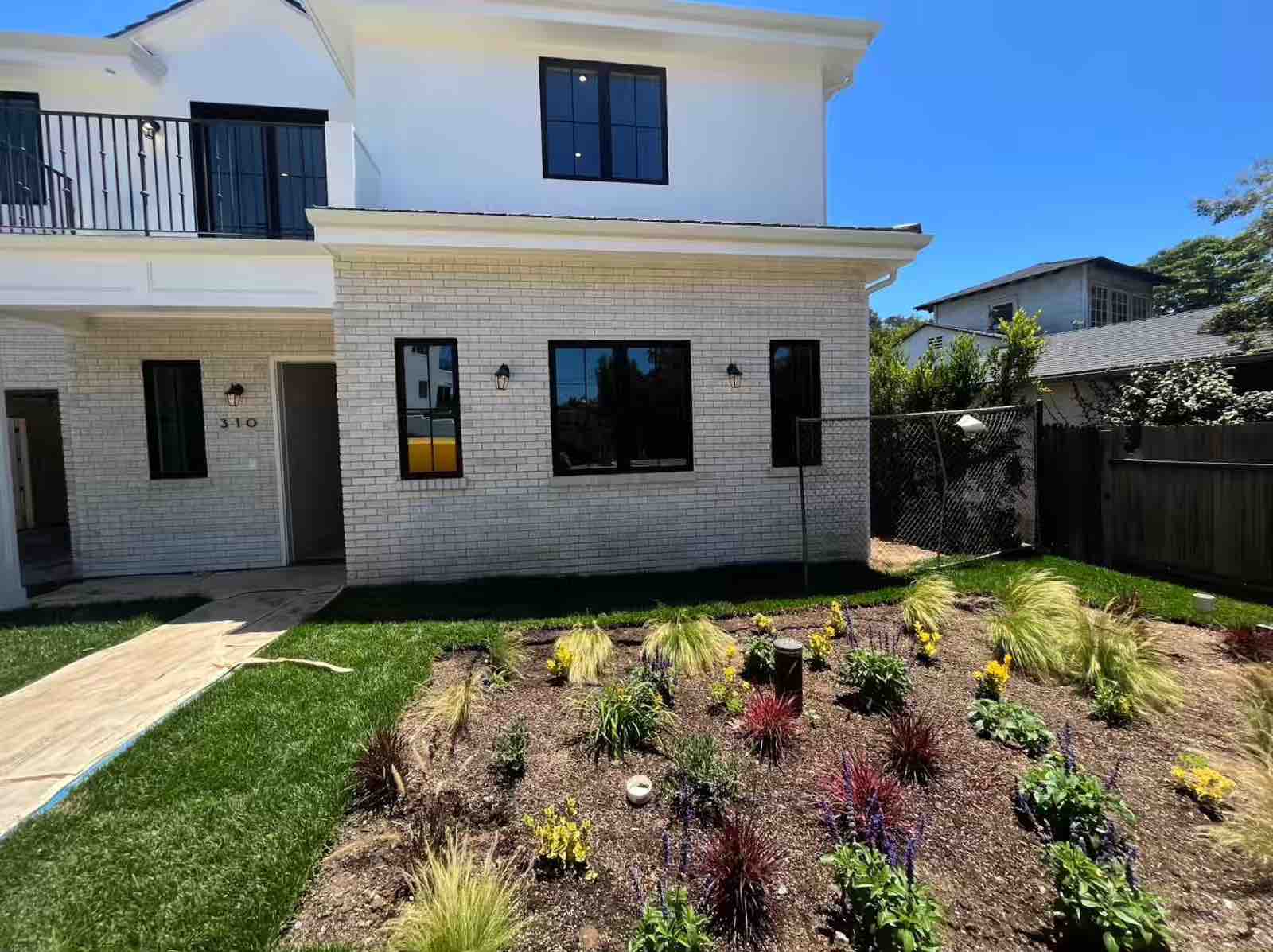 Pasadena two-story room addition with white brick exterior, newly planted landscape garden, and black-framed windows