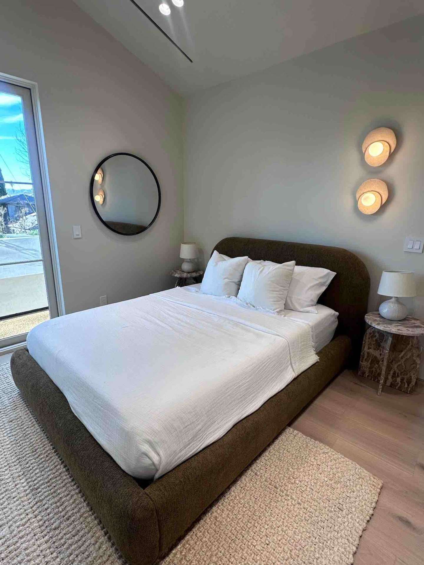 Encino ADU bedroom with modern upholstered bed, globe sconces, and floor-to-ceiling glass door
