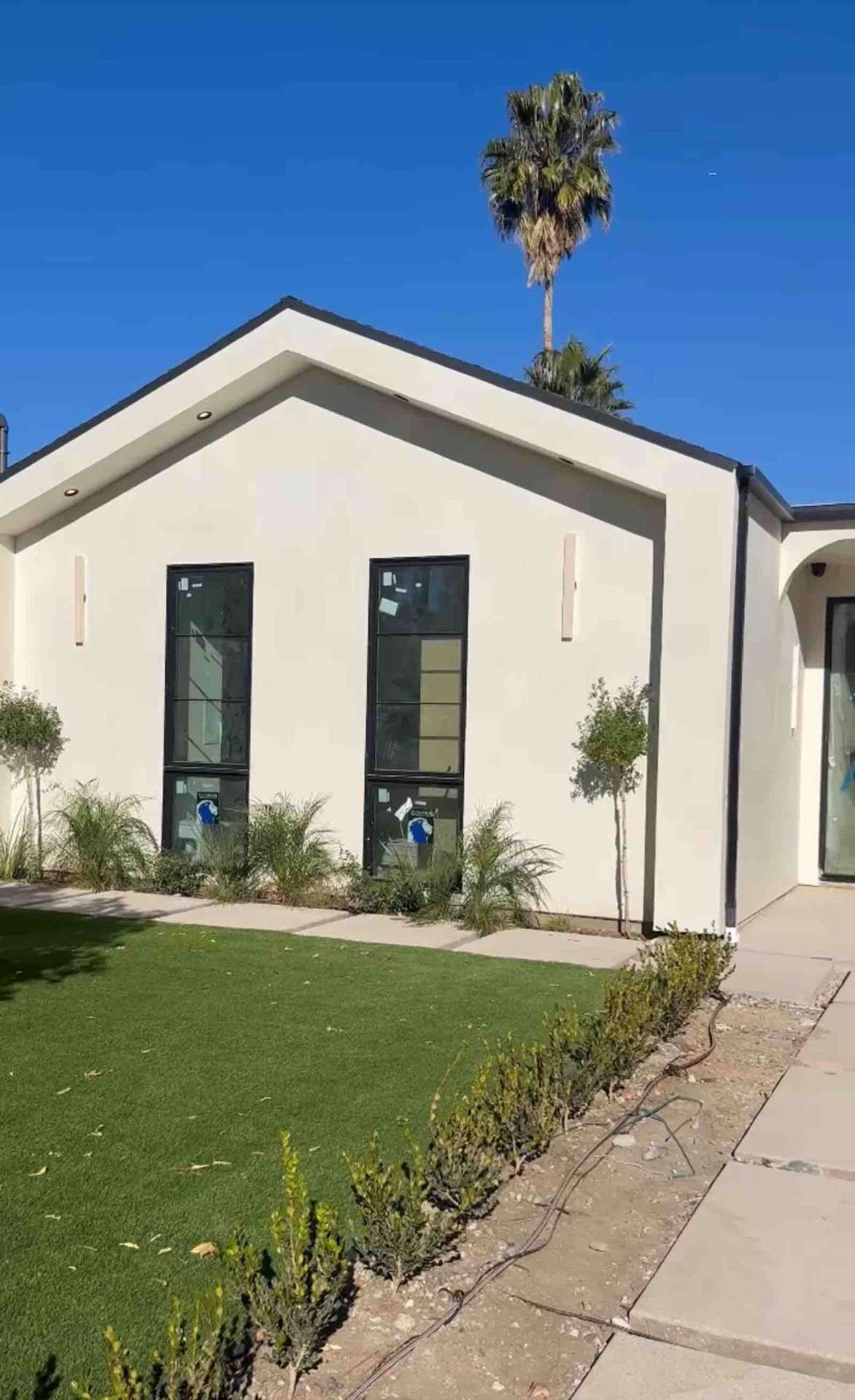 Encino ADU exterior with white stucco, black-framed floor-to-ceiling windows, and turf landscaping
