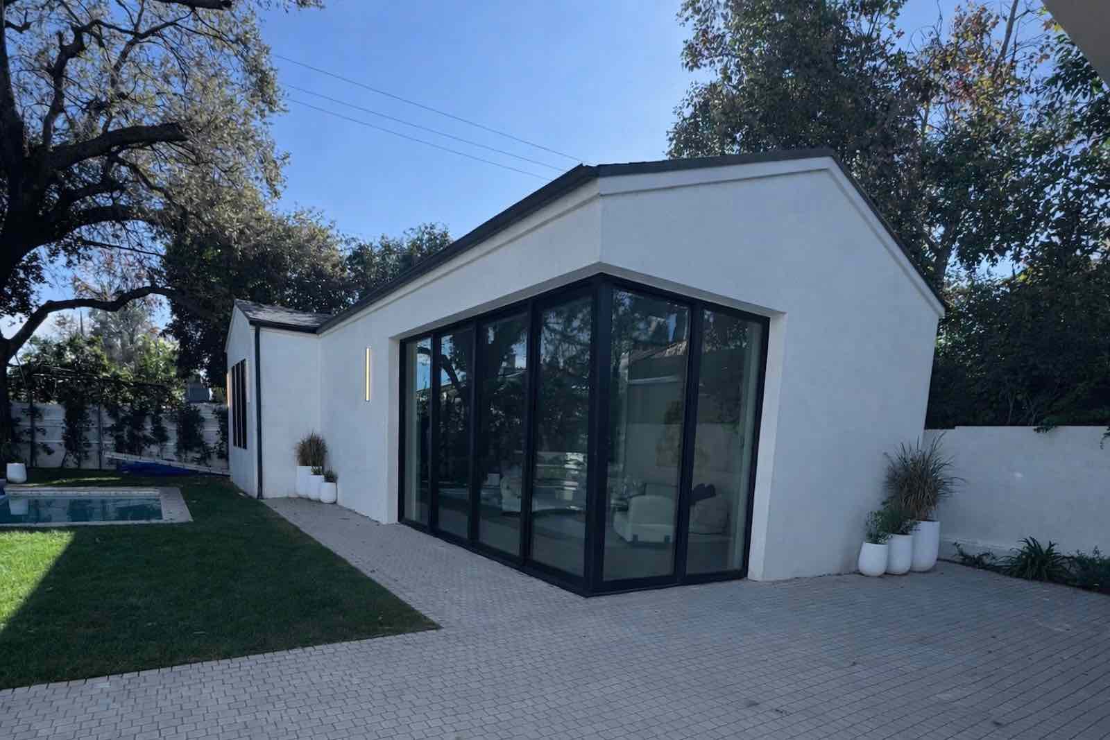 Encino ADU exterior with corner glass walls, poolside patio, and brick paver hardscape