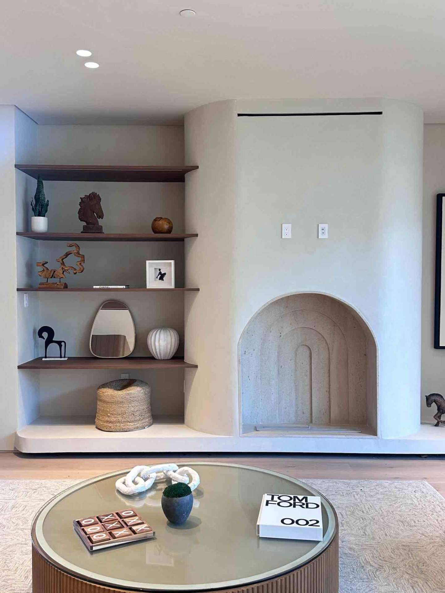 Encino ADU living room with sculptural arched fireplace, floating walnut shelves, and modern decor