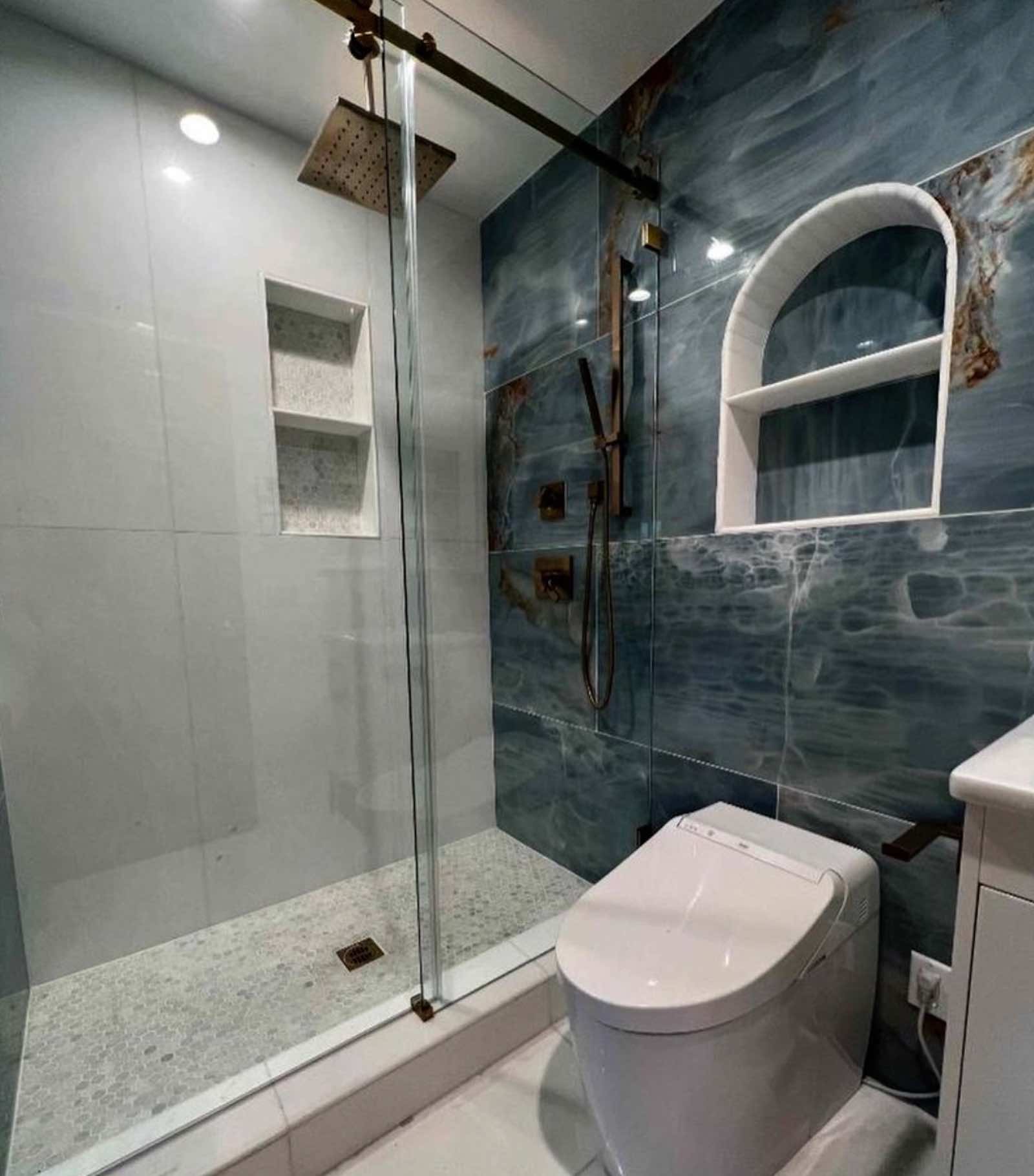 Alhambra bathroom shower with arched niche, blue onyx accent wall, and brass fixtures
