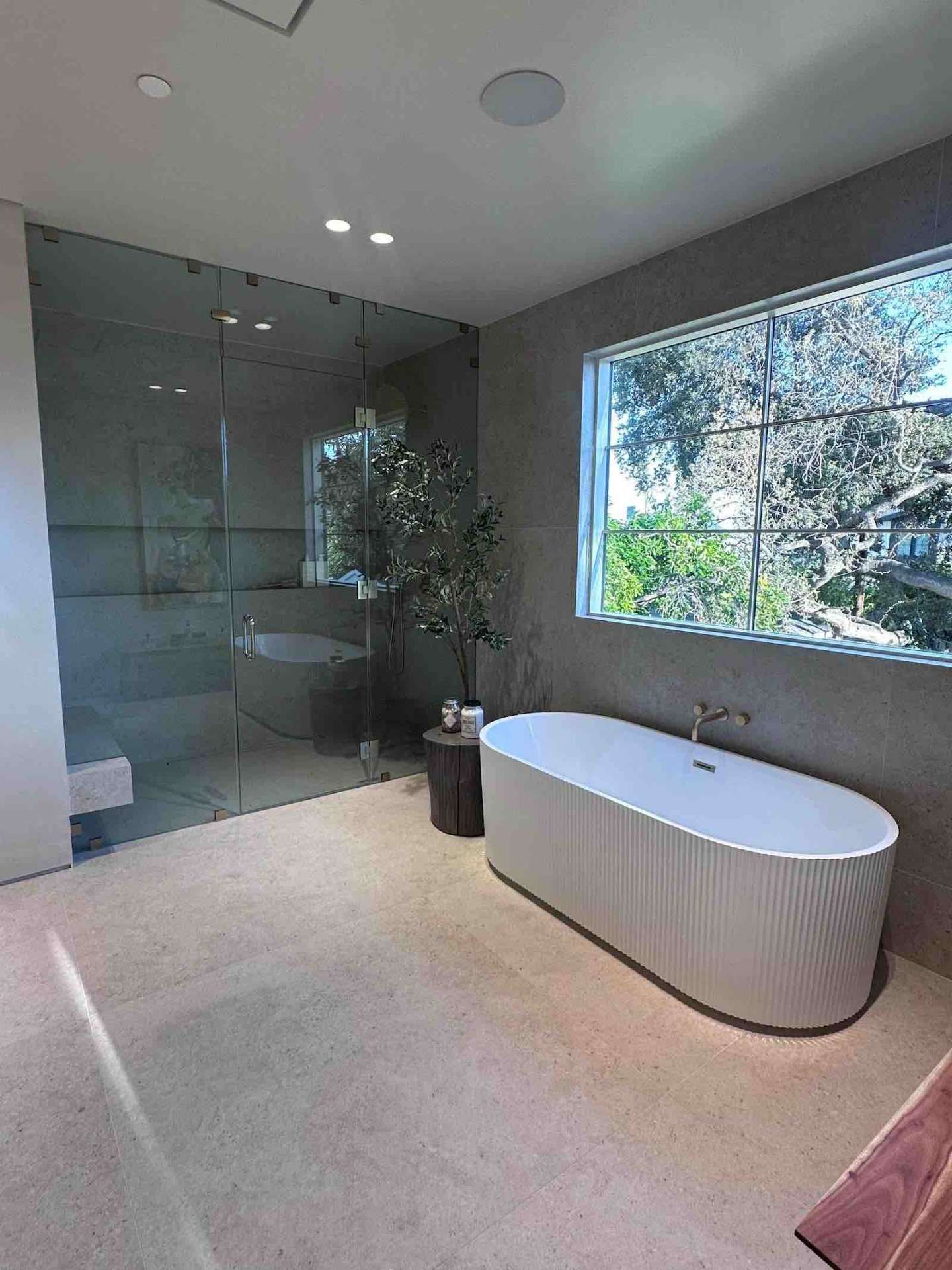Encino spa bathroom with freestanding ribbed tub, glass shower, and limestone floor
