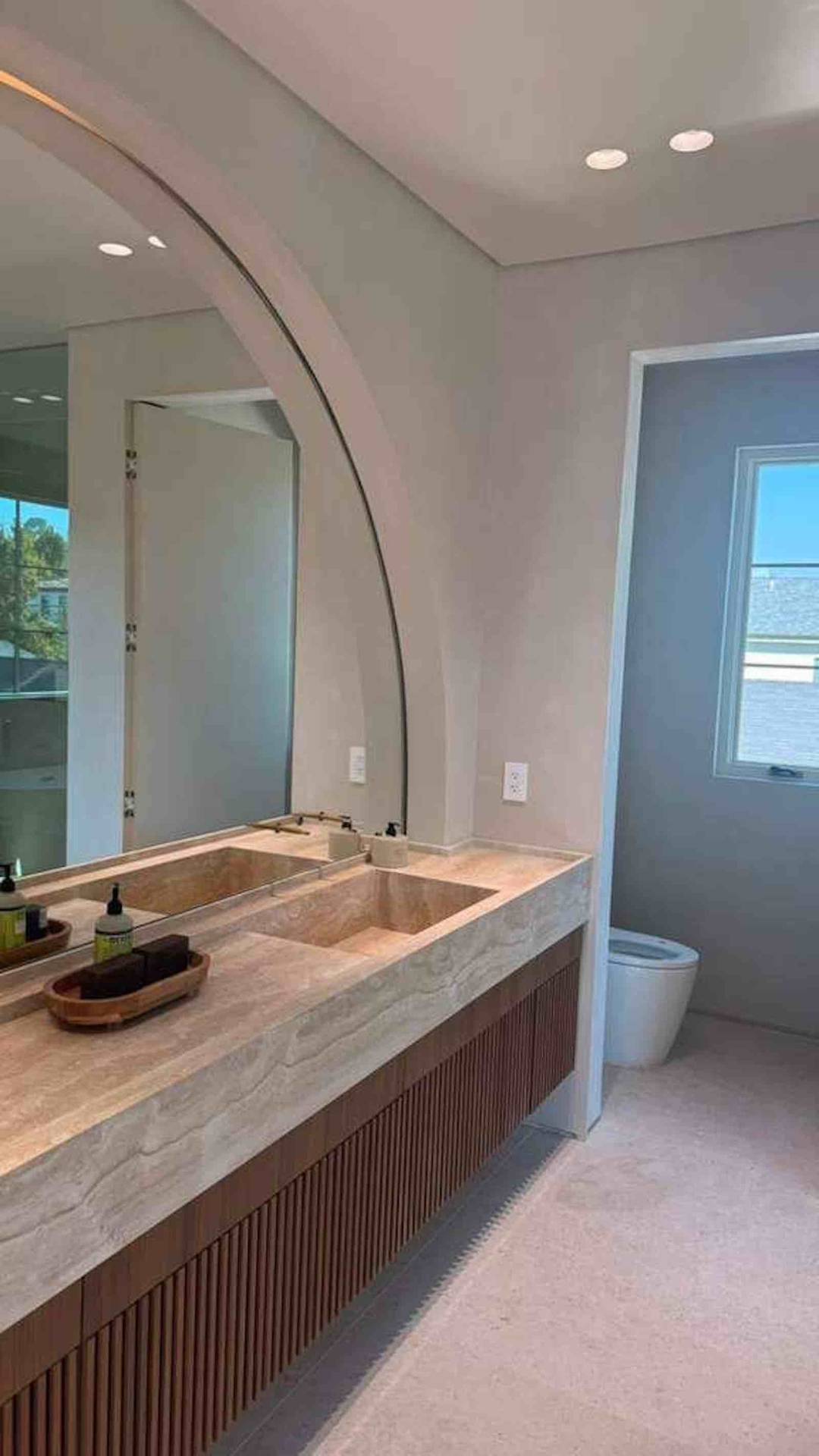 Encino master bathroom travertine double vanity with arch mirror and fluted walnut cabinet