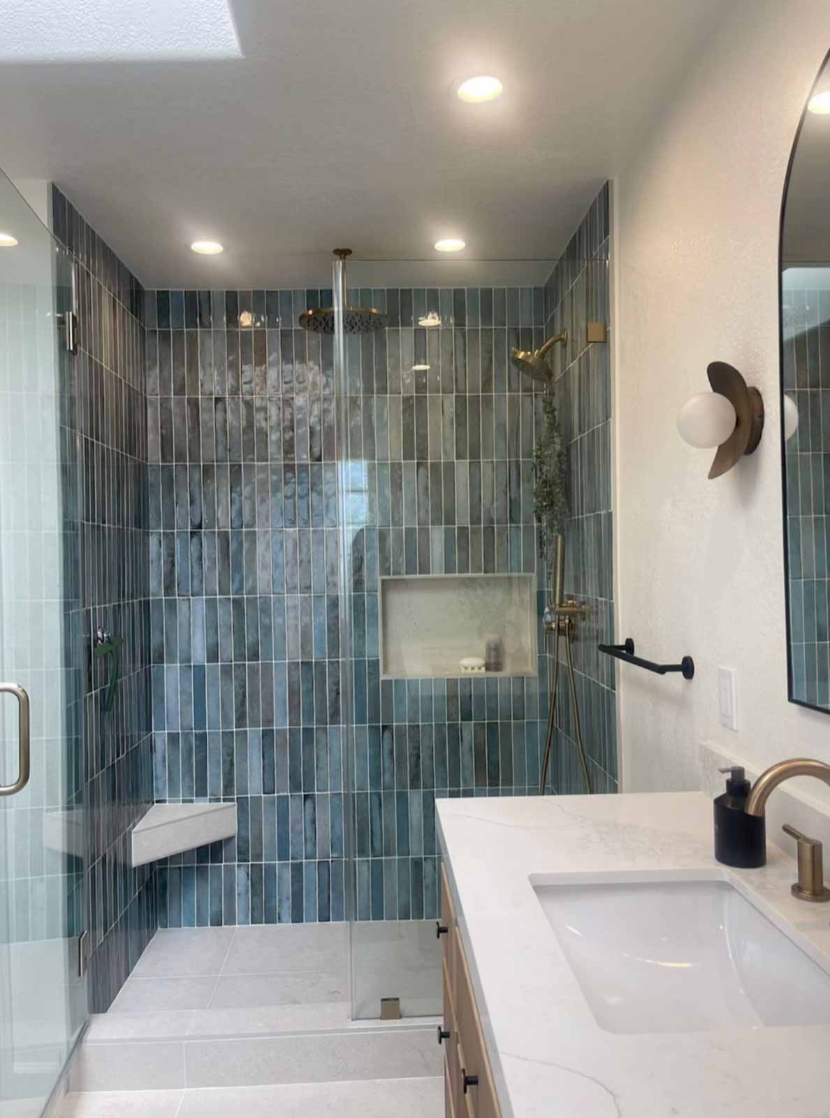 Blue subway tile shower with brass rain head, bench seat, and glass door - Glendale remodel