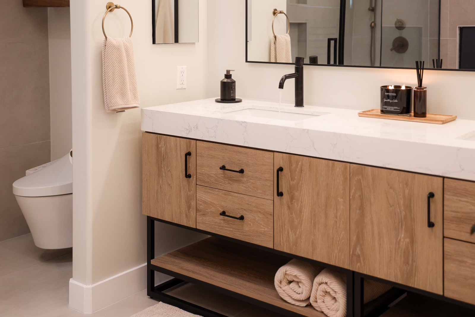 Long Beach bathroom with oak vanity, marble top, black hardware, and glass shower