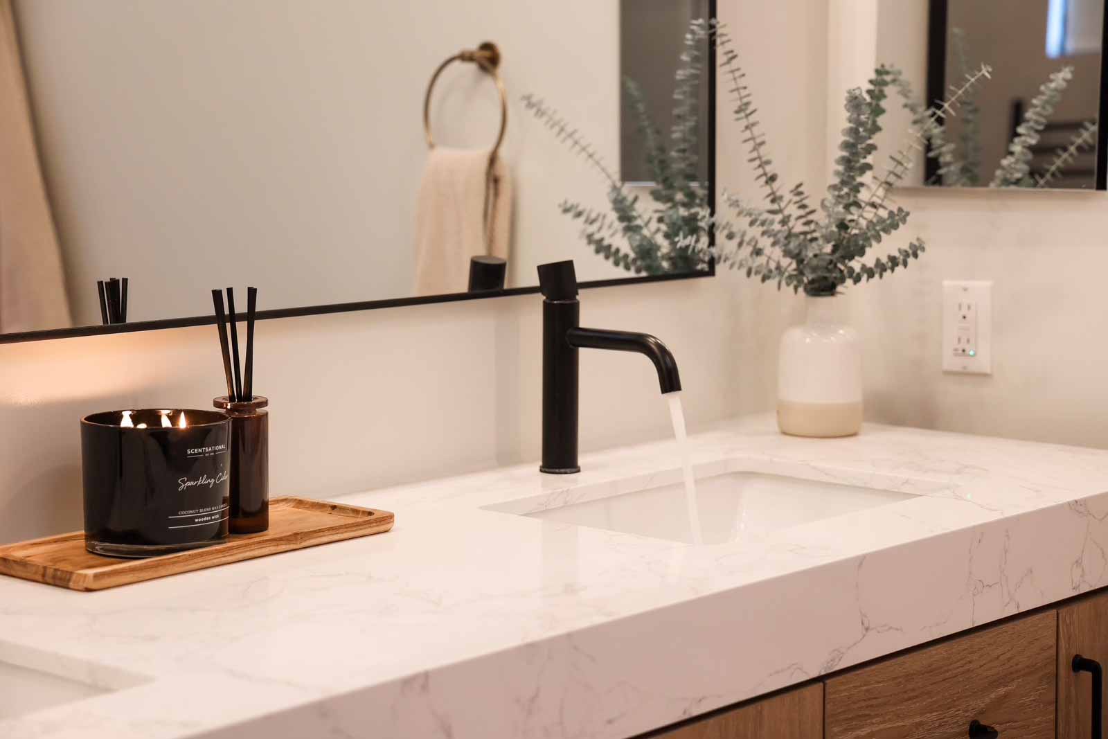 Contemporary bathroom detail with black faucet, eucalyptus plant, and quartz countertop
