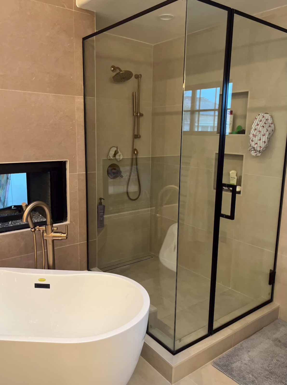 Luxury Long Beach bathroom with freestanding tub, built-in fireplace, and black-framed shower
