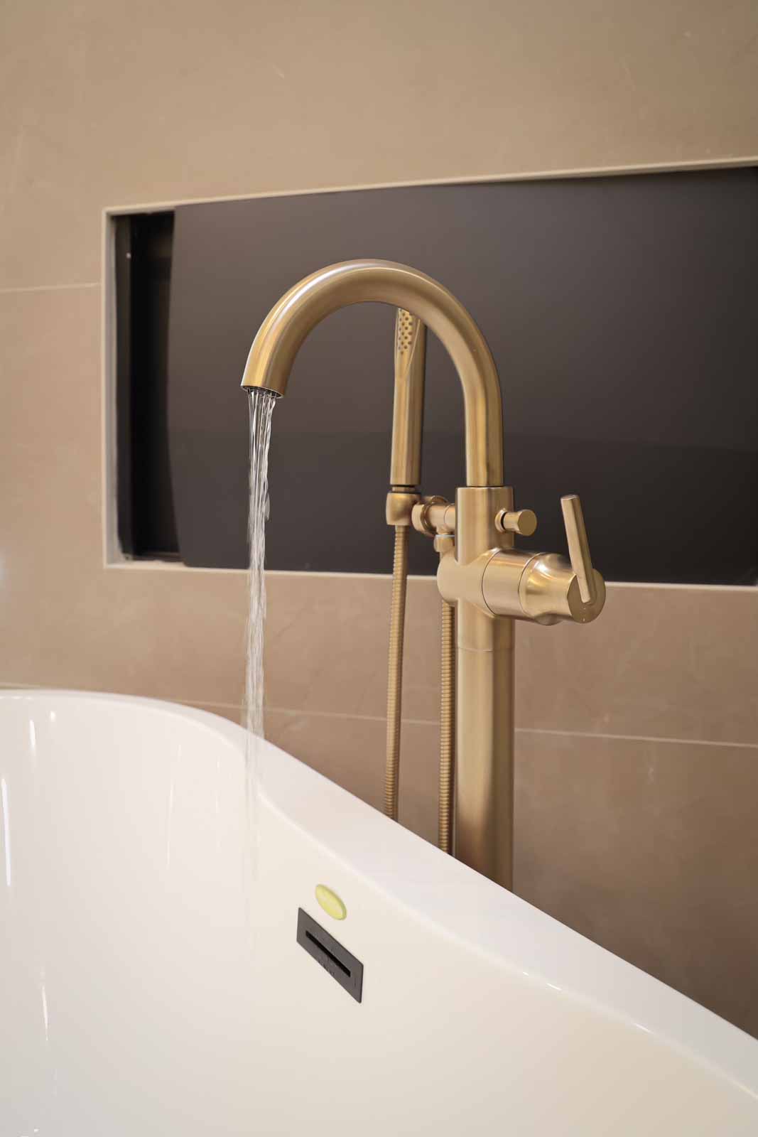 Champagne gold tub faucet detail with built-in fireplace backdrop - Long Beach remodel