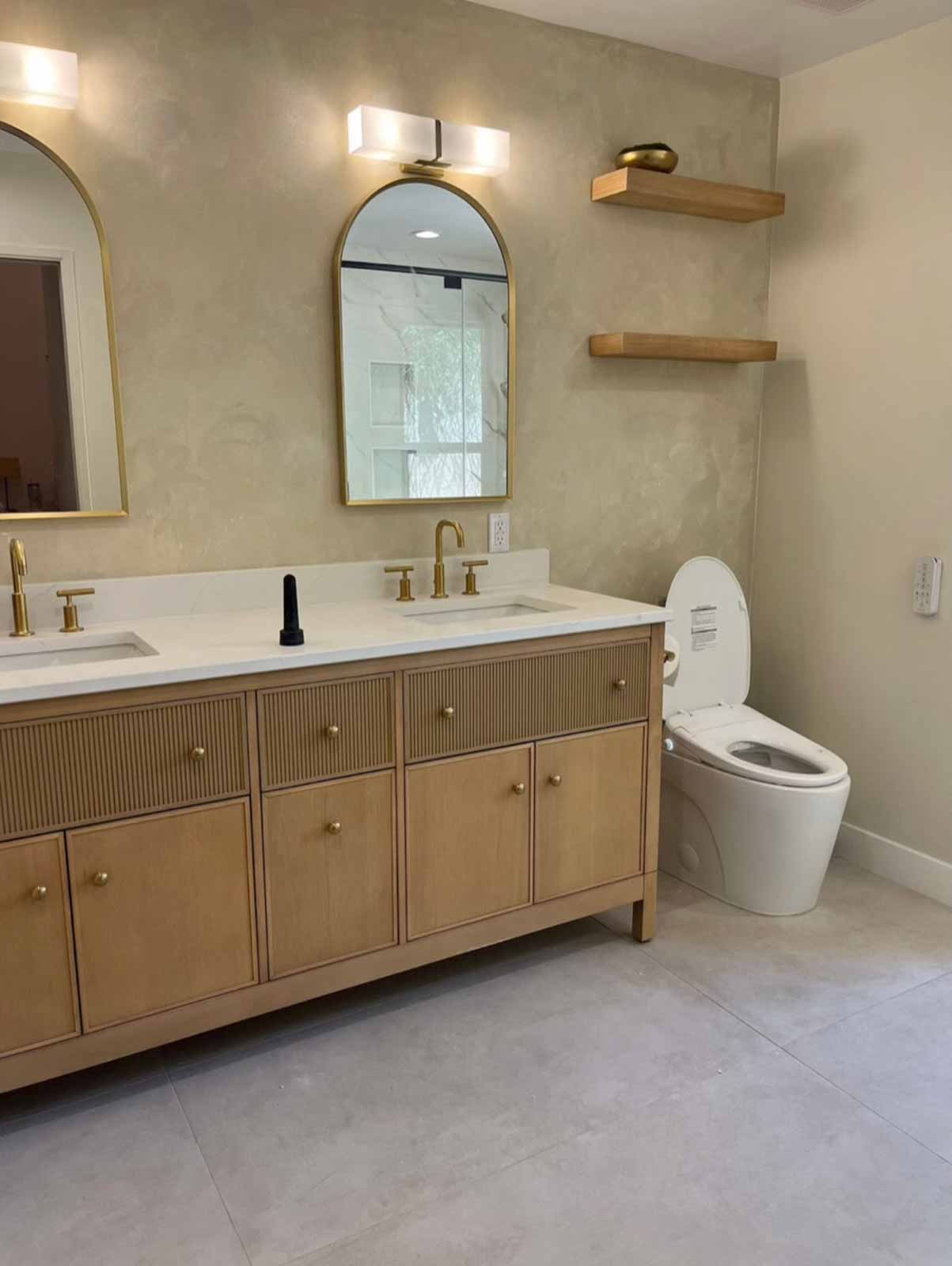 Double vanity with arch mirrors, oak fluted cabinets, and brass fixtures - Los Angeles bathroom