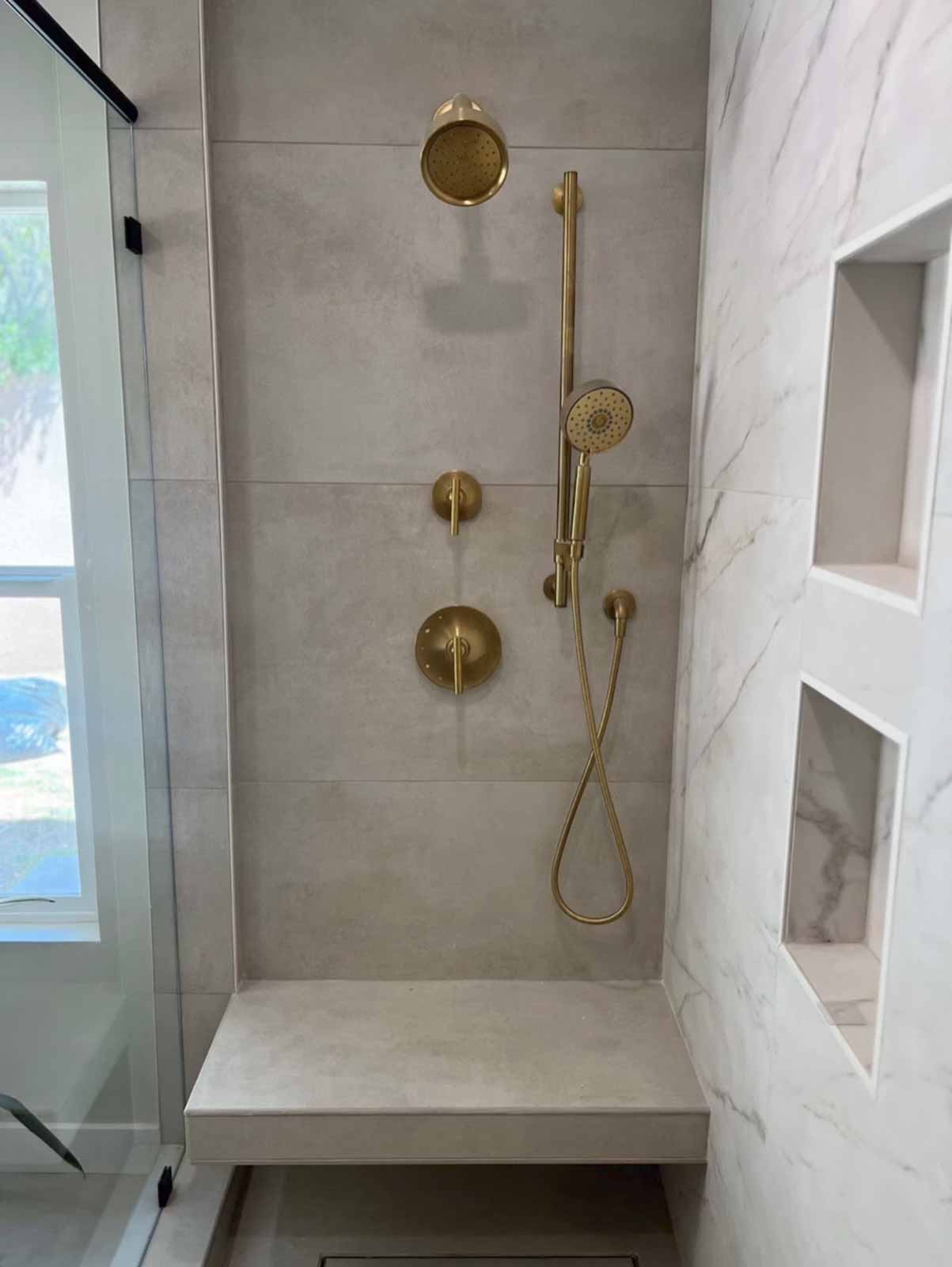 Shower corner with brass fixtures, handheld shower, and marble bench seat - LA remodel