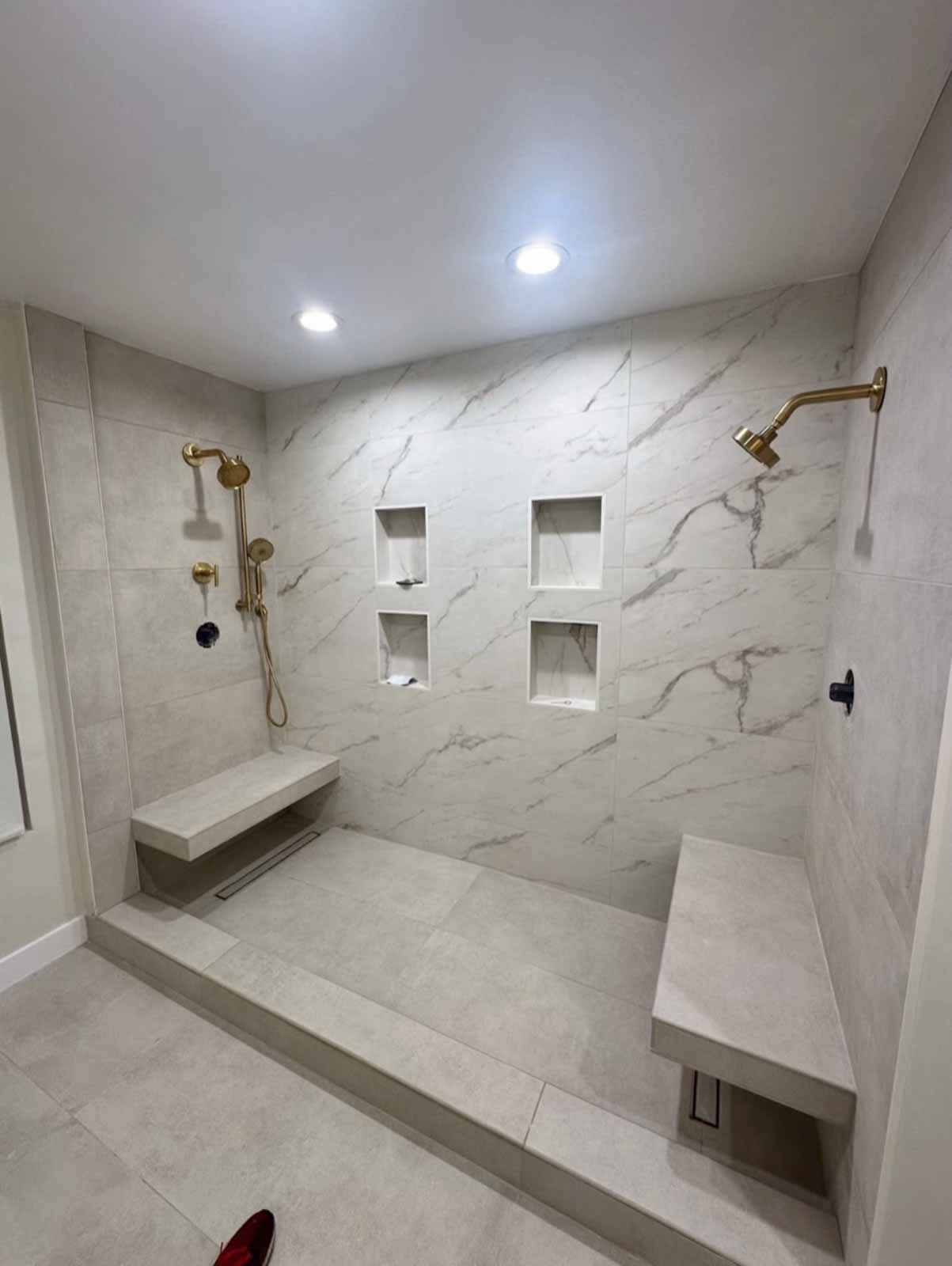Spacious Los Angeles walk-in shower with dual showerheads, corner benches, and marble tile