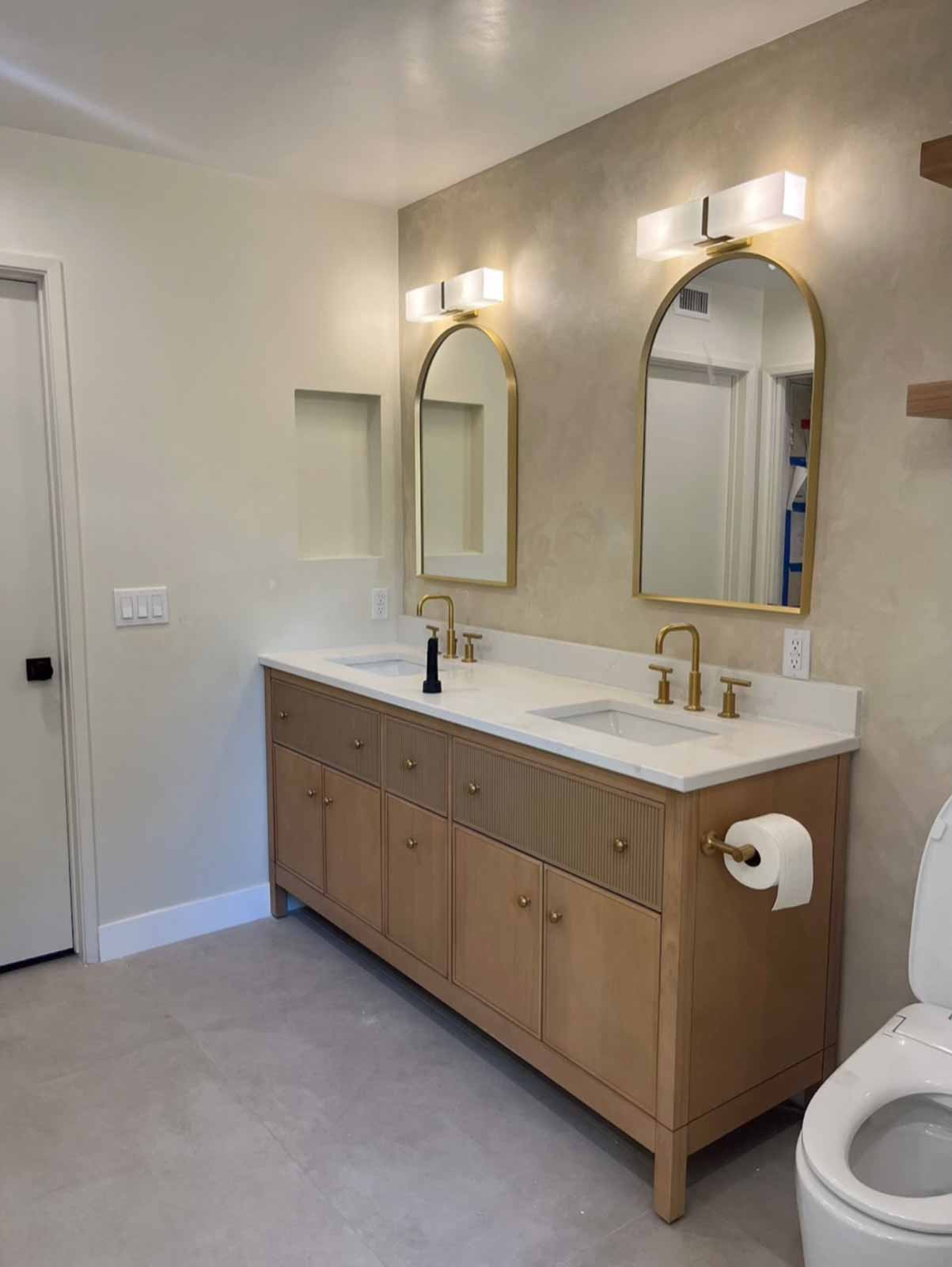 Los Angeles bathroom with oak double vanity, arch mirrors, and venetian plaster walls