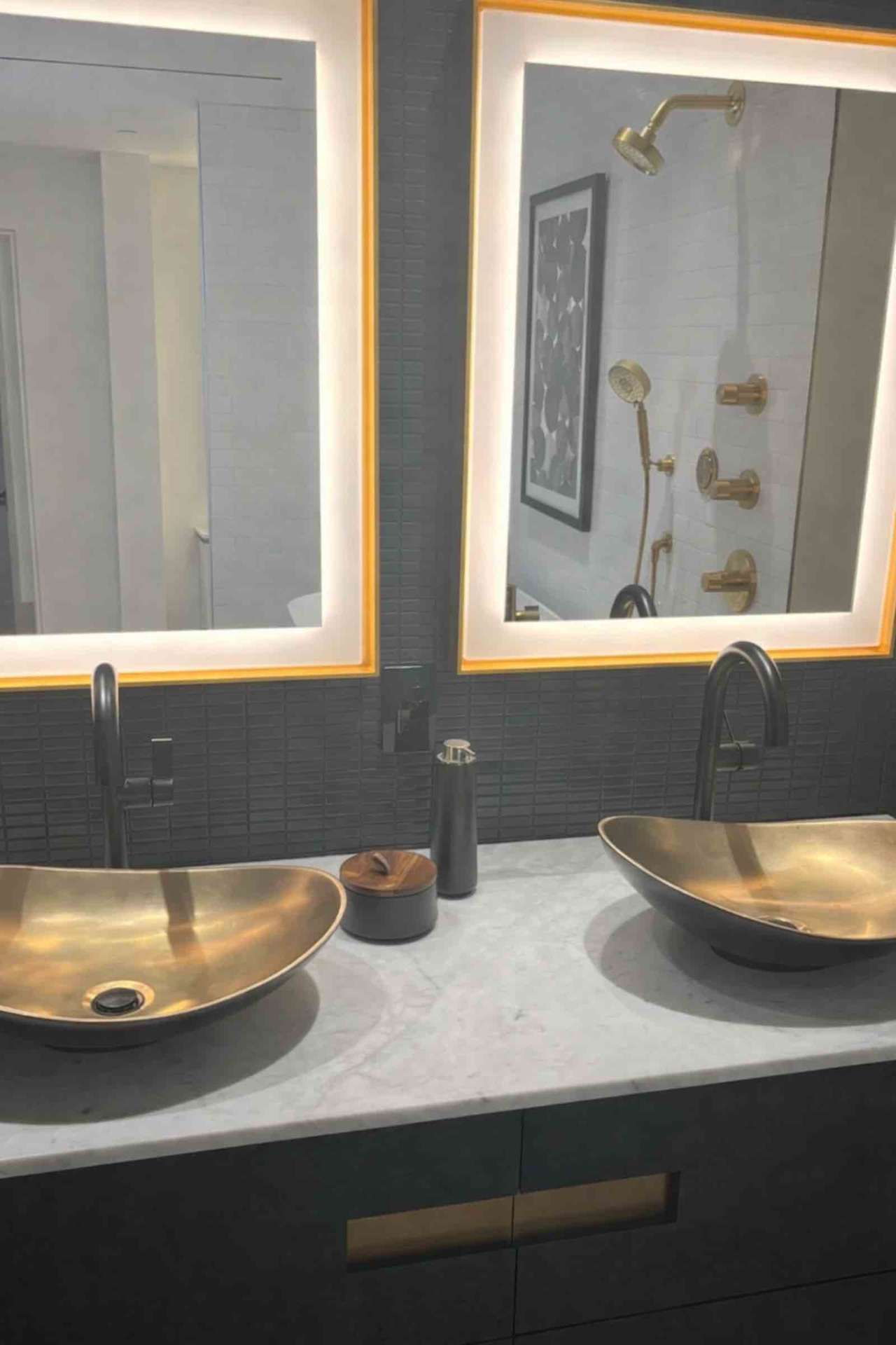 Mulholland Drive bathroom with brass vessel sinks, LED backlit mirrors, and dark tile backsplash