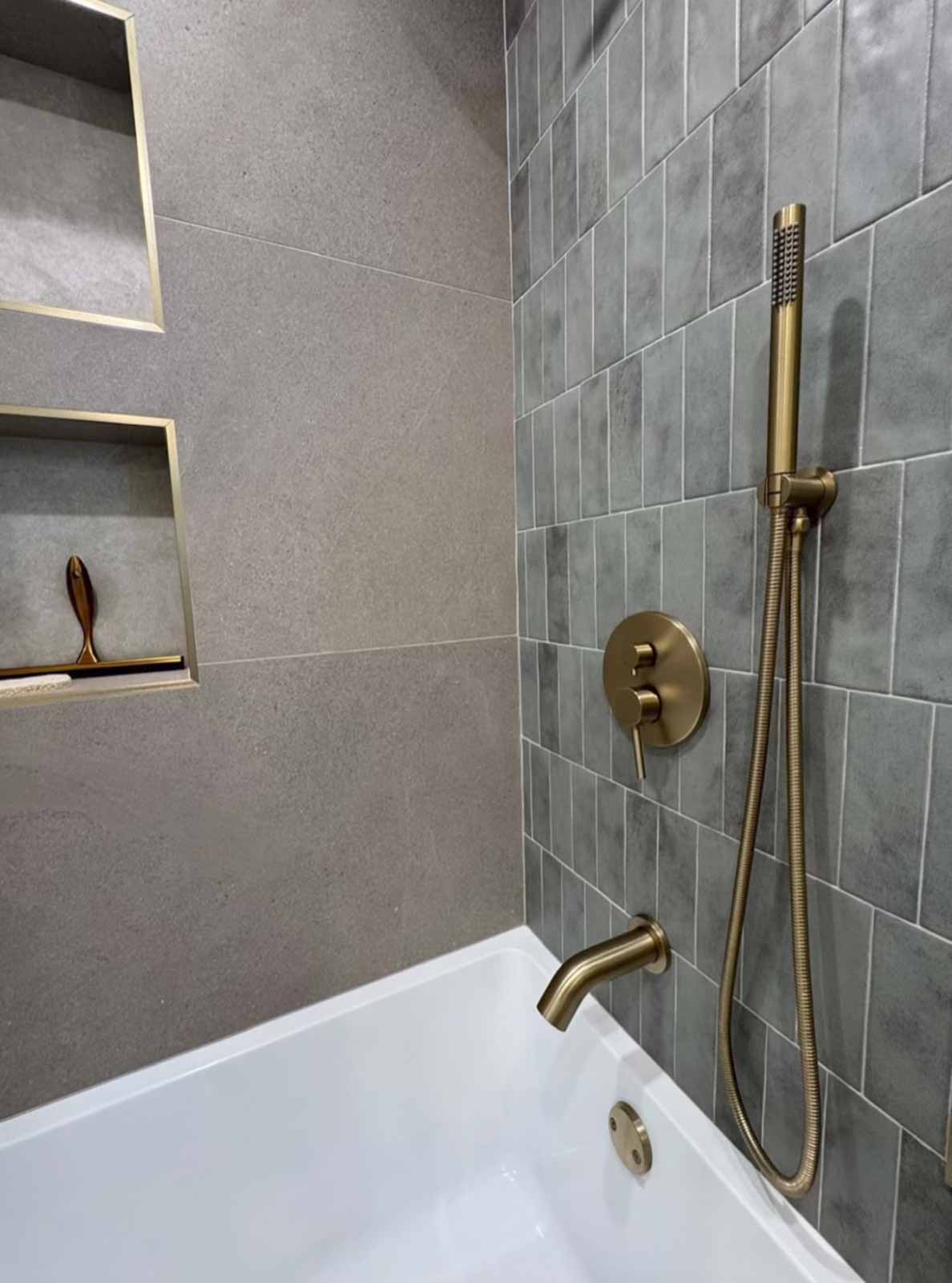 Shower detail with gray subway tile, brass hand shower, and built-in niche - Pasadena