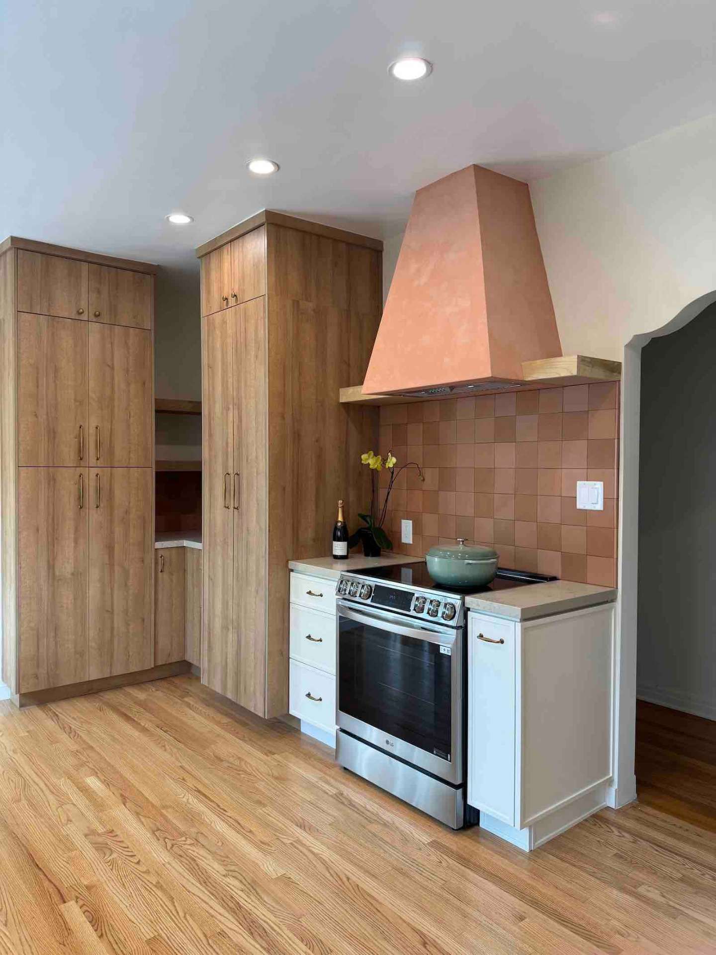 Rancho Park kitchen terracotta plaster range hood with oak tall storage