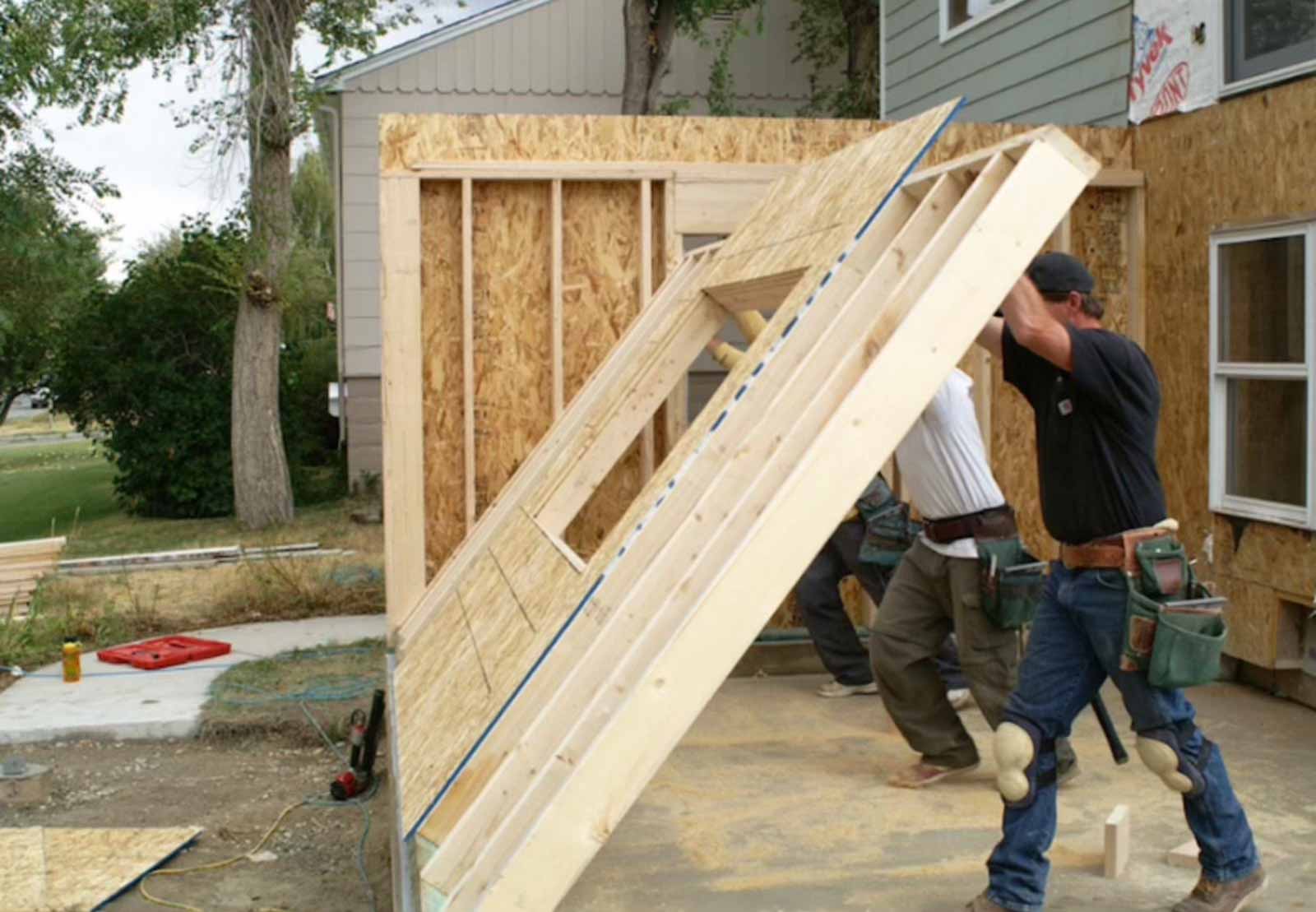 Wall panel installation for room addition showing OSB sheathing and construction crew - LA home addition contractor